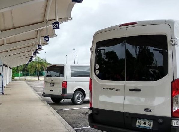 Two transportation vans parked in Cancun Airport parking lot