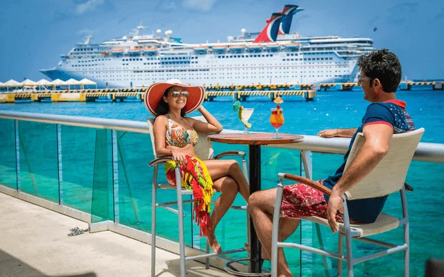 A couple enjoying the view of a cruise at Cozumel while having one drink. One of the destinations available for Cancun Airport Transportation