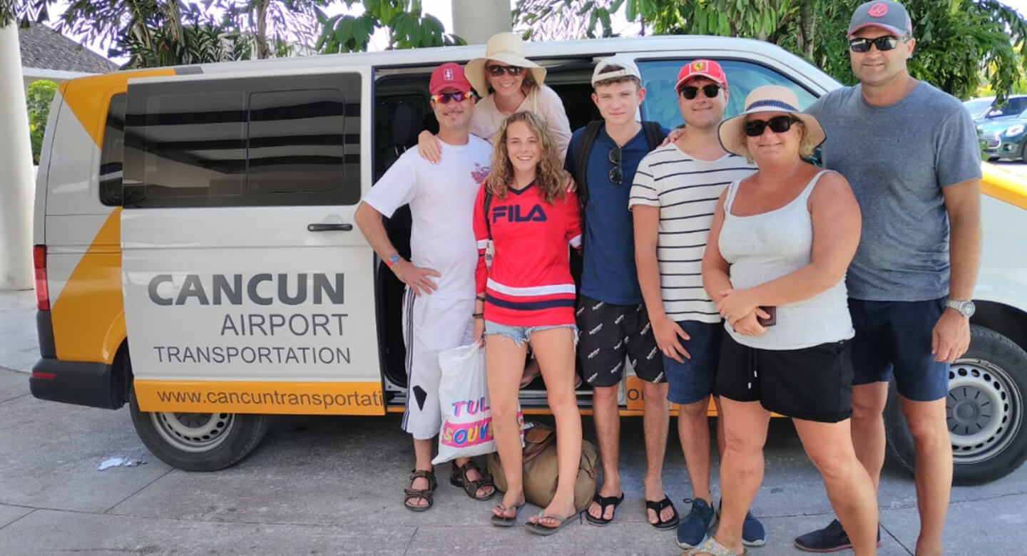 Seven happy customers in front of a van labeled by Cancun Airport Transportation