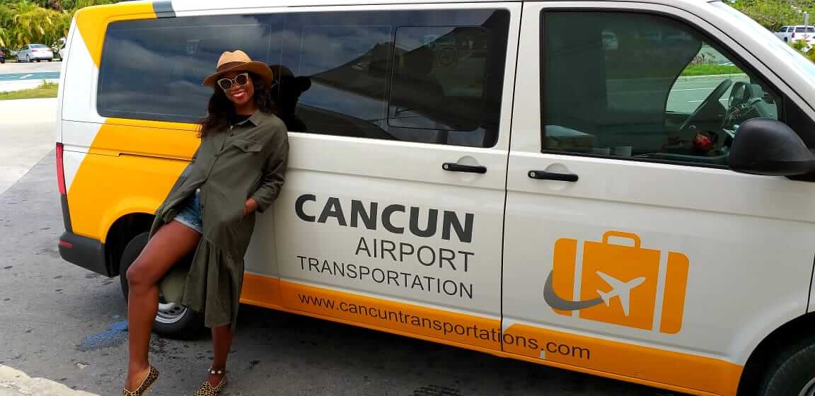 Young woman reposing over Cancun Airport Transportation van and smiling
